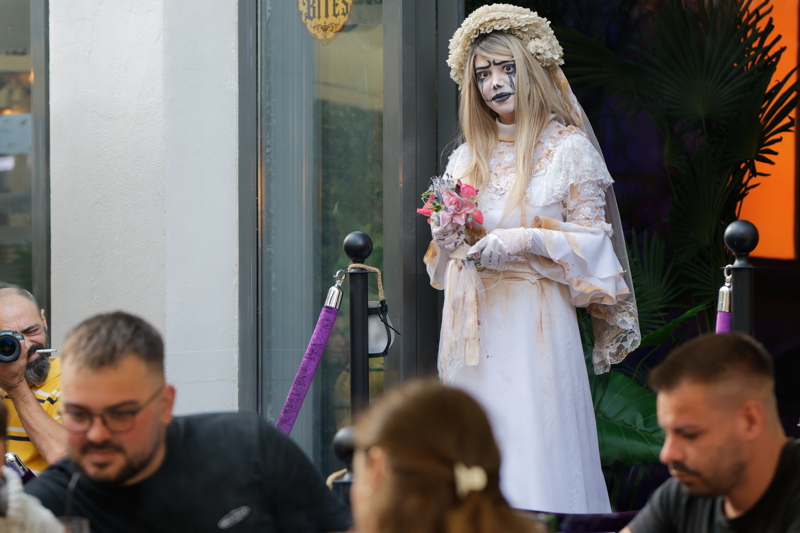 A costumed performer dressed as the Corpse Bride (Emily) standing outside Rose's Mystery House in the Old Town of Bucharest